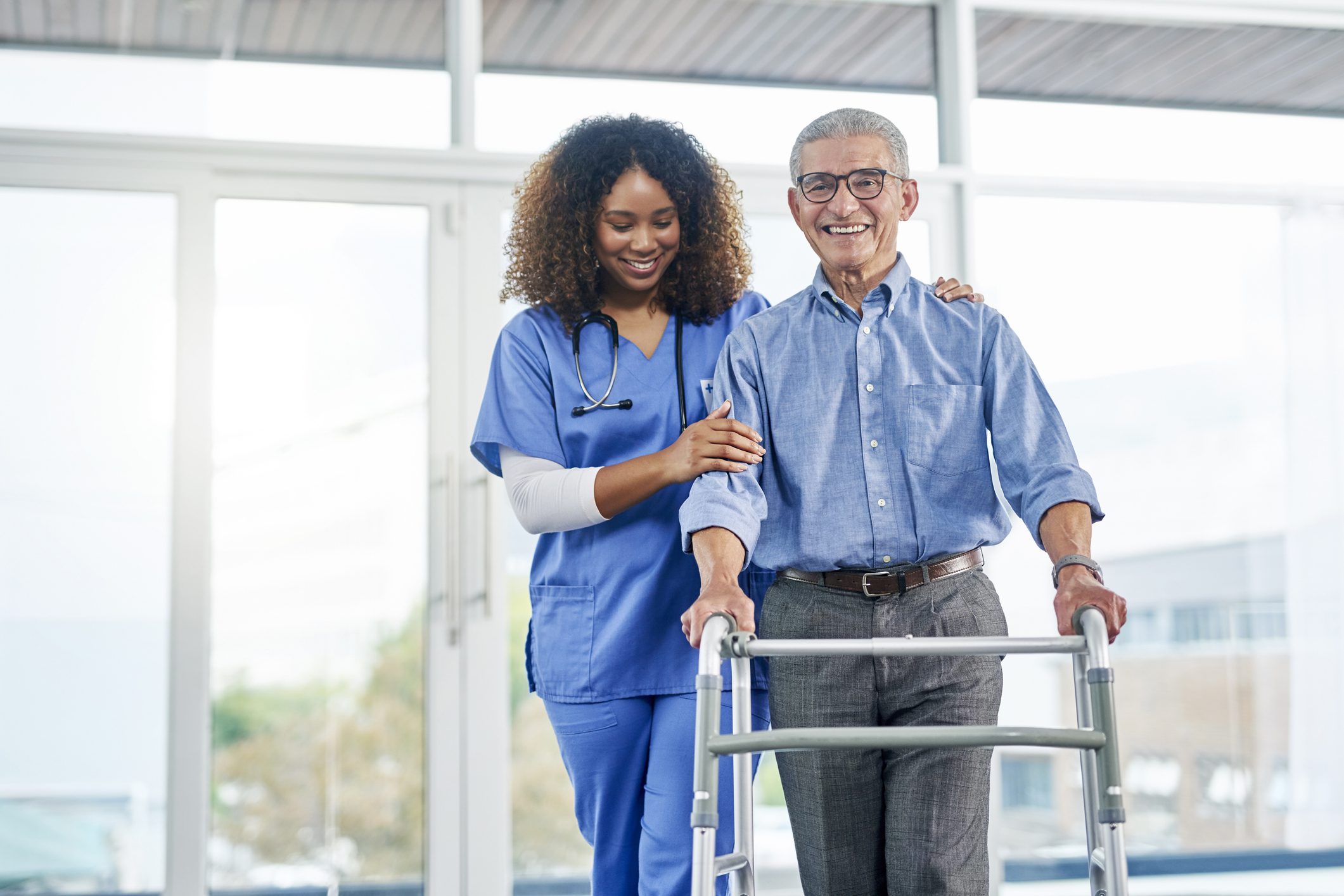 Shot of an attractive young female nurse assisting a senior patient walk using a walking frame at a hospital