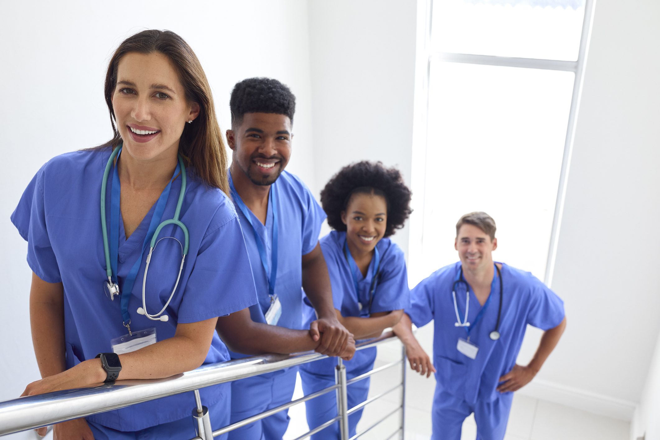 Portrait Of Multi Cultural Medical Team Wearing Scrubs Standing On Stairs In Hospital